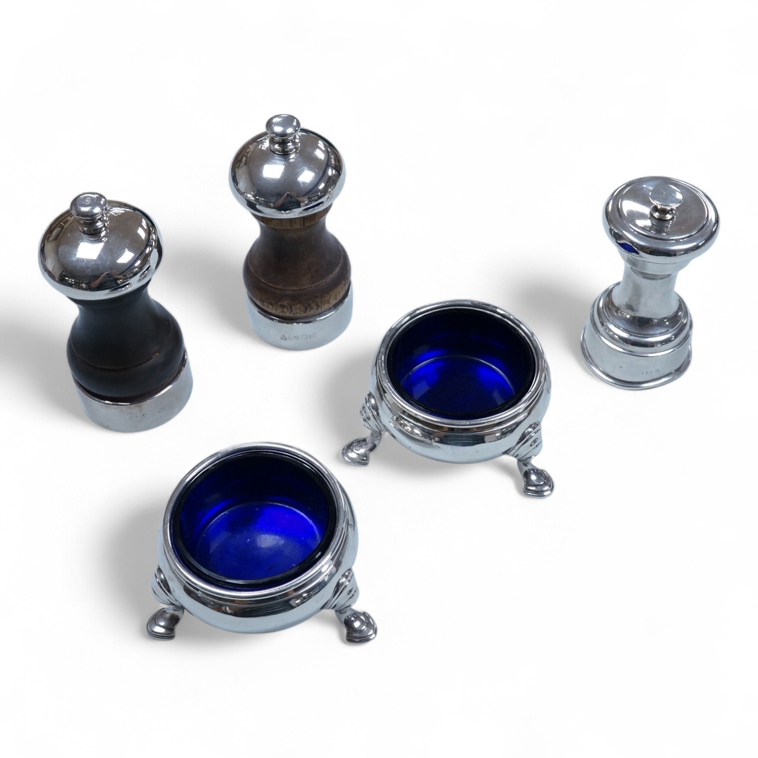 Two modern silver mounted pepper mills, 10.5cm, one other silver pepper mill by Hukin & Heath, Birmingham, 1926 and a pair of George III silver bun shaped salts, David Hennell I, London, 1750, with blue glass liners.